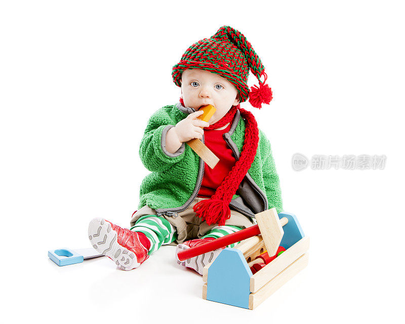 装扮成圣诞精灵的男婴使用工具制作玩具