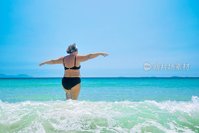 成熟的女人穿着泳装在海边。