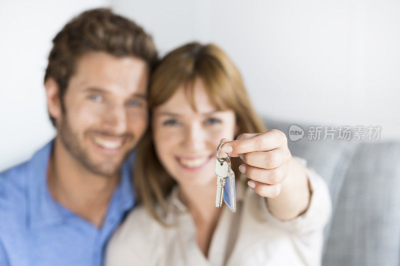 一对兴高采烈的年轻夫妇正在展示他们新公寓的钥匙