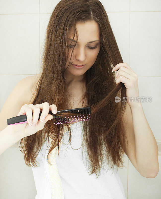 年轻的黑发女子正在梳理她美丽的长发