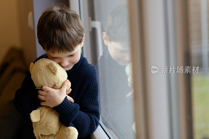 悲伤的男孩抱着他的泰迪熊。