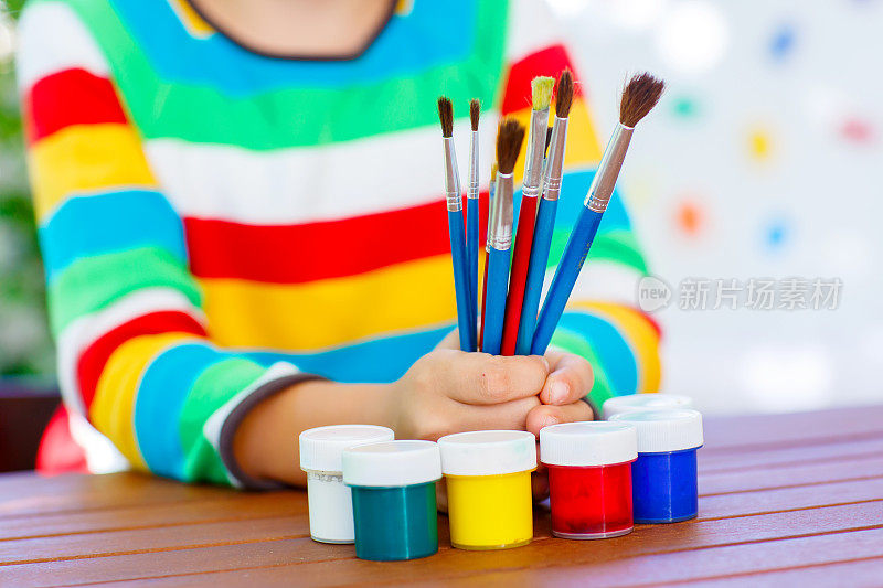 孩子的手有很多刷子和彩色水彩画
