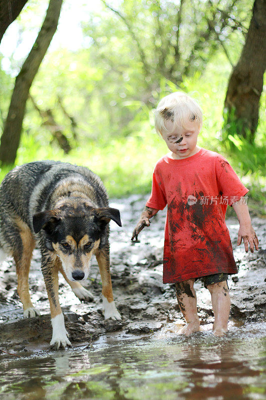 小孩和狗在泥泞的河里玩耍