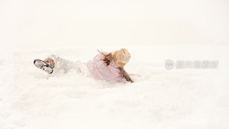 小女孩高兴地在雪地里打滚