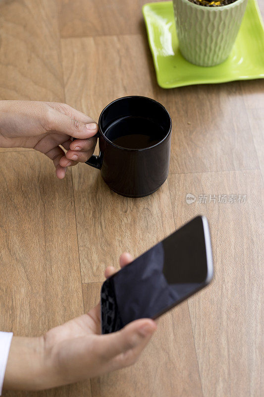 女商人一边喝咖啡一边玩智能手机