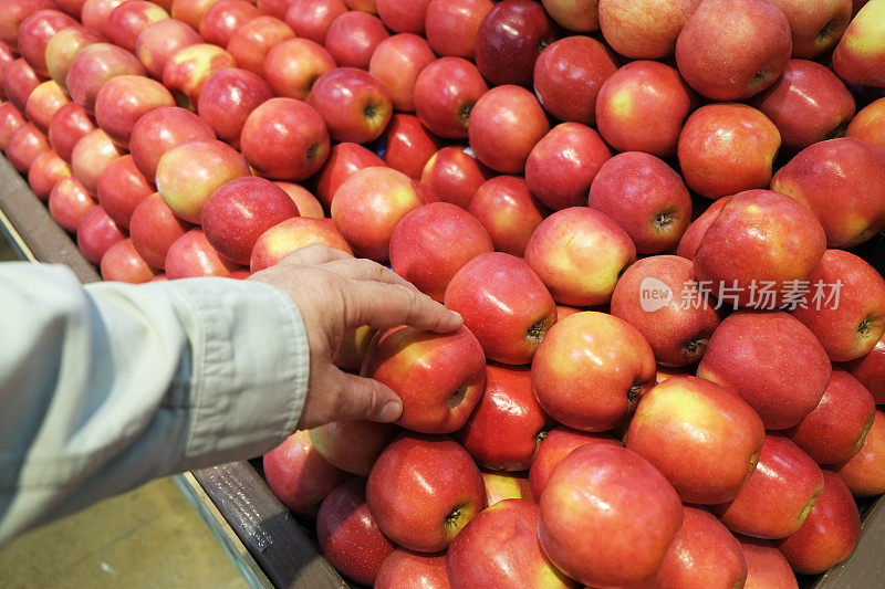 一个男人在商店里拿红苹果