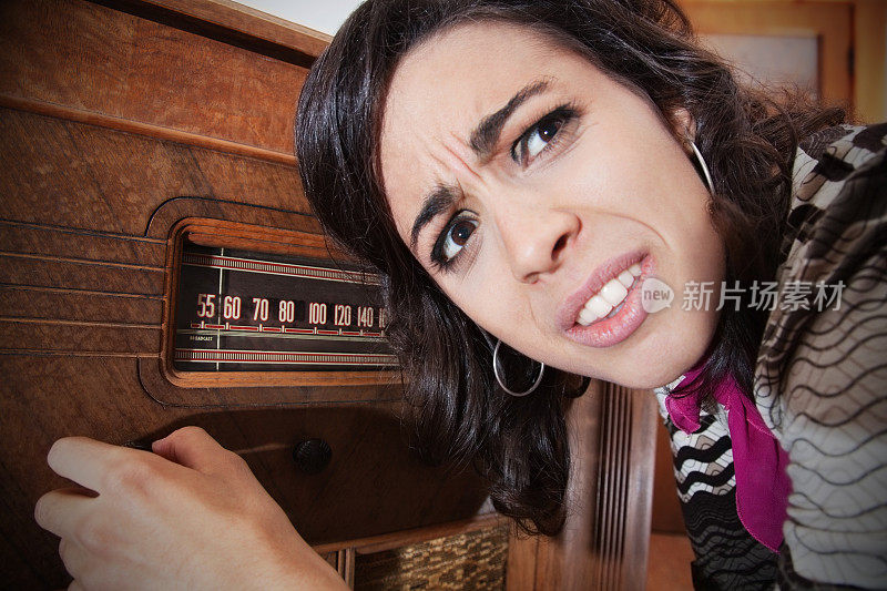 困惑的女人试图操作老式收音机