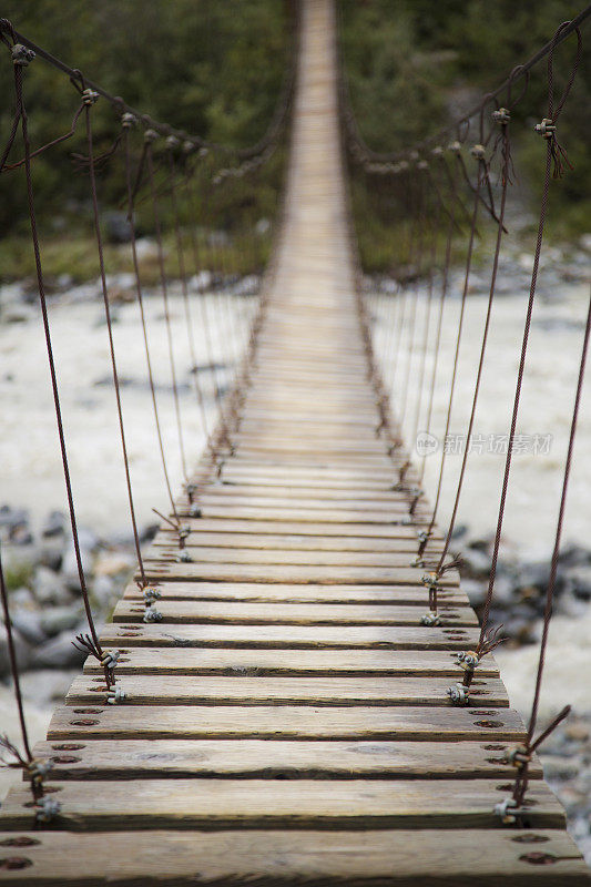 木制悬索桥横跨一条流淌的河流在阿尔
