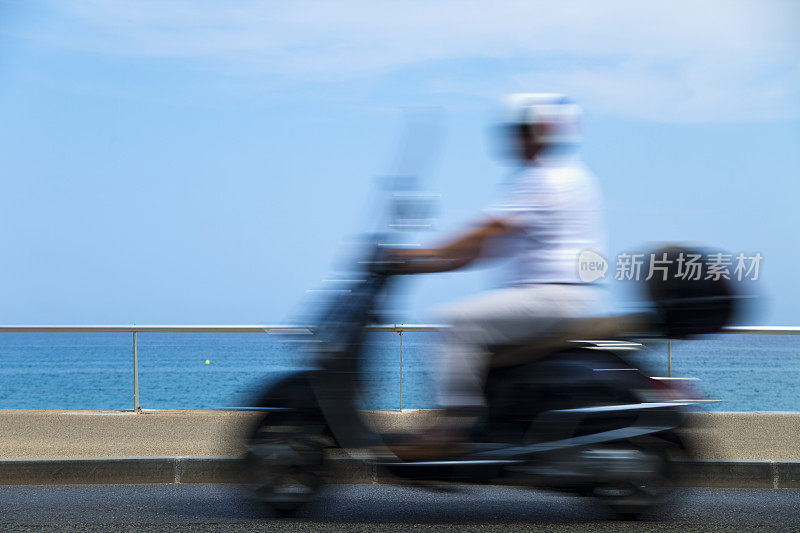 沿着海岸公路骑摩托车的人，动态模糊