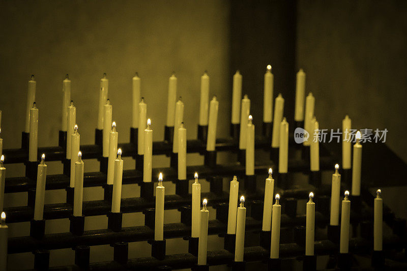 在黑暗的教堂里，成排的蜡烛燃烧着