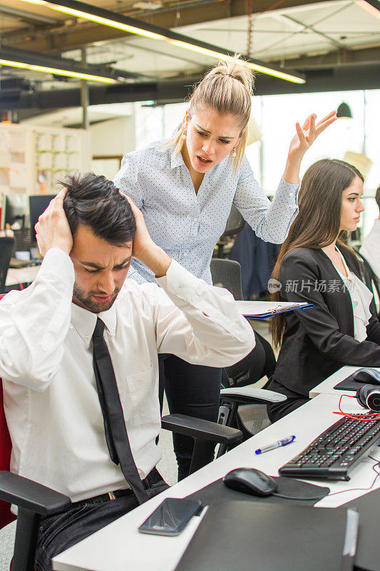 一个愤怒的女商人在办公室对一个压力很大的员工大喊大叫。