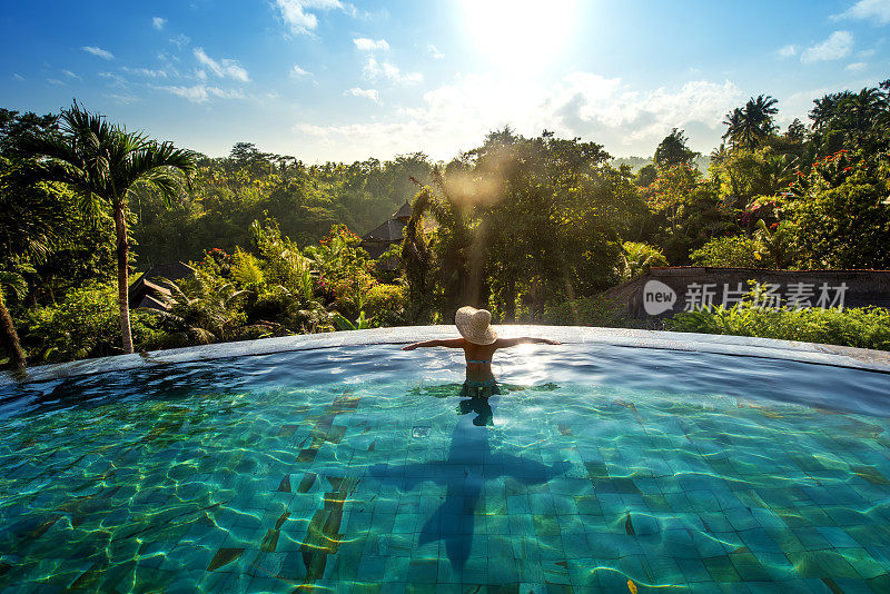 幸福的概念。在豪华度假村的游泳池里享受日光浴的女人