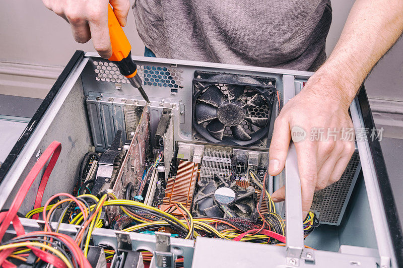 一个用螺丝刀修理旧台式电脑的人