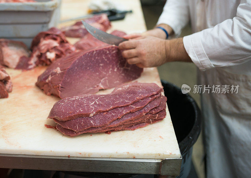 屠夫正在切上面的圆牛排