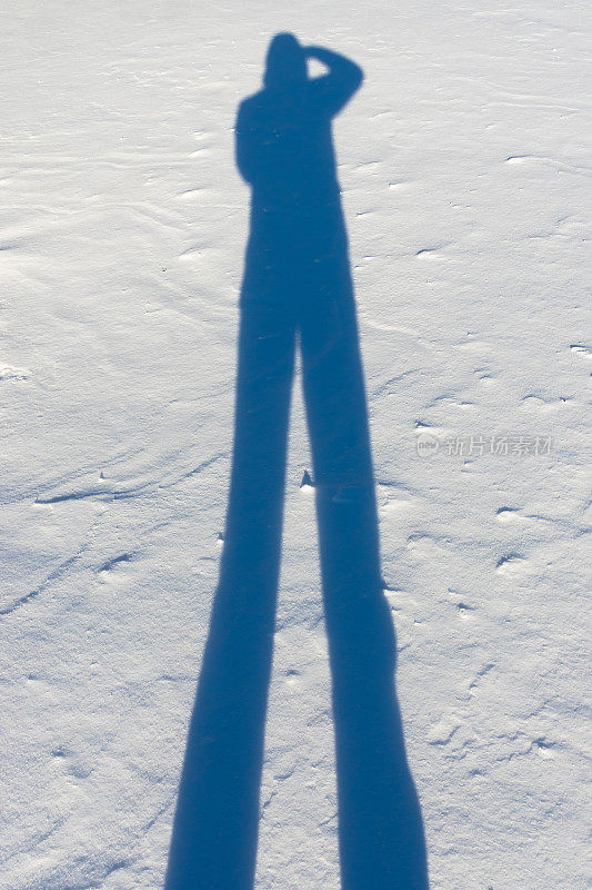 夕阳的余晖投射在雪地上的成年男性的影子