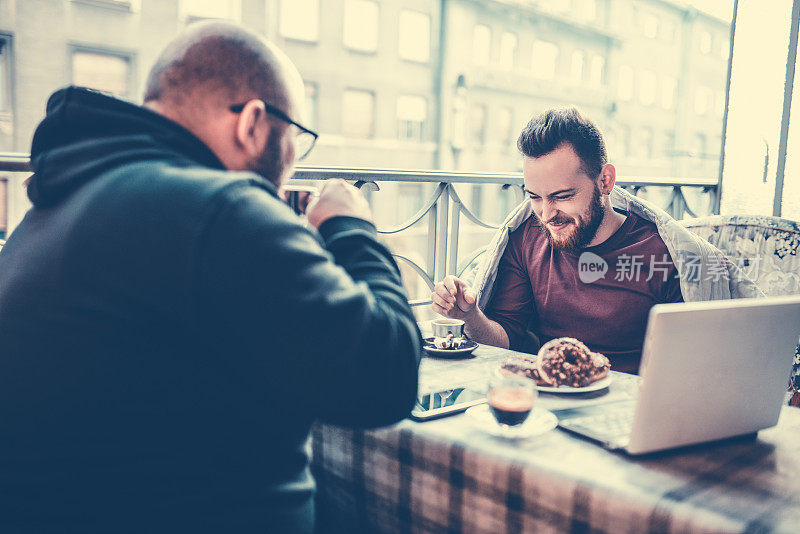 两位男同事在阳台上喝咖啡吃早餐