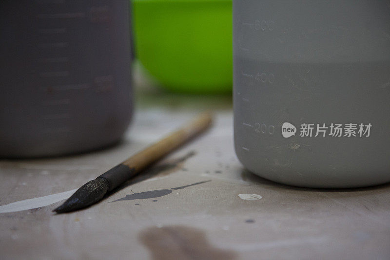 在艺术家工作室里，艺术家的画笔被釉瓶包围