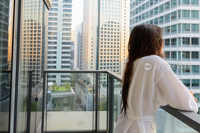 年轻美丽的亚洲女人从阳台上欣赏城市的景色