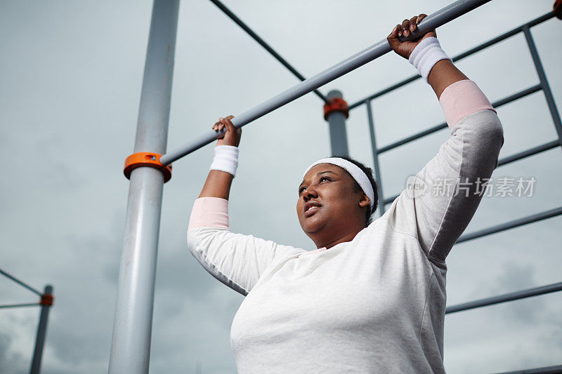 决心超重的非洲妇女在户外练习引体向上运动