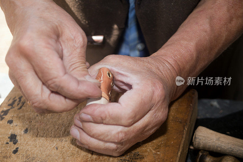 鞋匠的手制造玩具迷你皮靴。