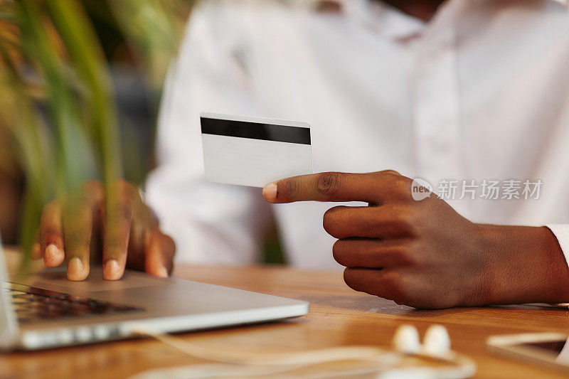非洲人在笔记本电脑上打字，用塑料卡付款