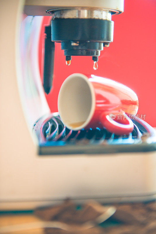 浓缩咖啡倒入一个红色的杯子和溢出，咖啡机，特写，红色背景