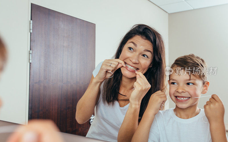 母亲和儿子用牙线清洁牙齿