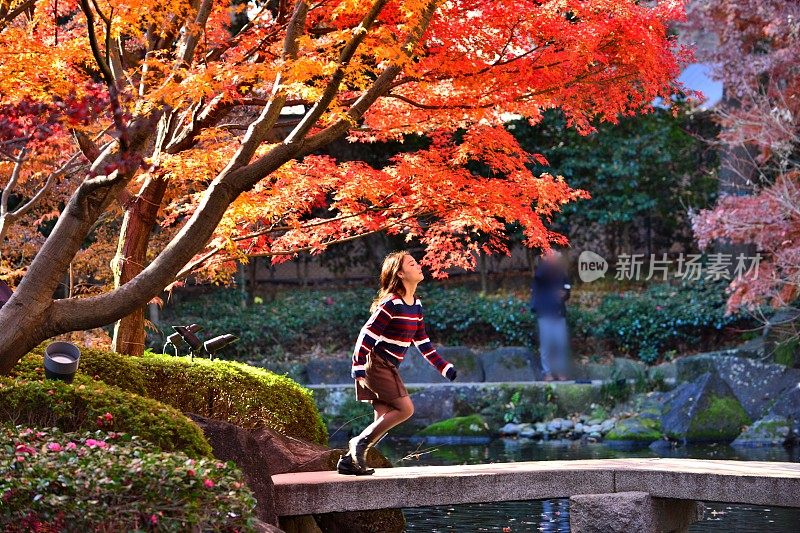 在东京日本花园的石桥上奔跑的年轻日本女人