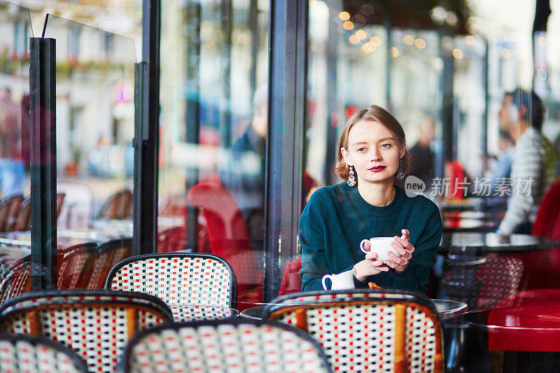 年轻优雅的女人在咖啡厅喝咖啡在巴黎，法国