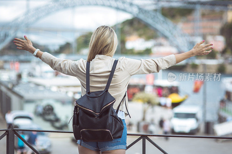 女人享受自由旅行，张开双臂拥抱城市