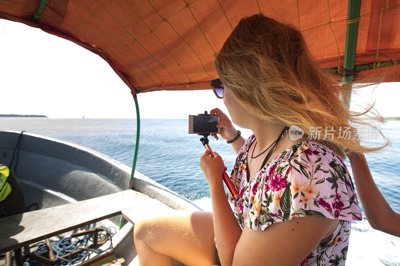 一名年轻女子在游船时用手机拍照