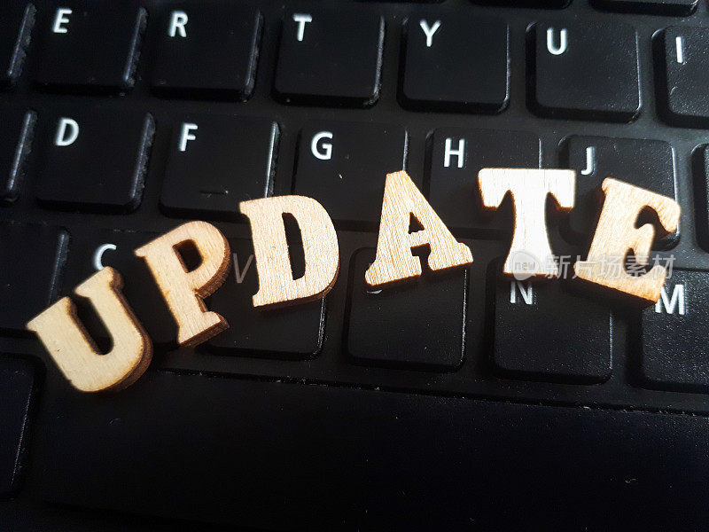 “update”这个词是由木制字母组成的。键盘背景木铭文
