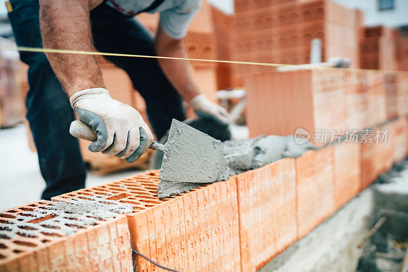 专业工人使用平底刀用水泥和灰浆建造砖墙