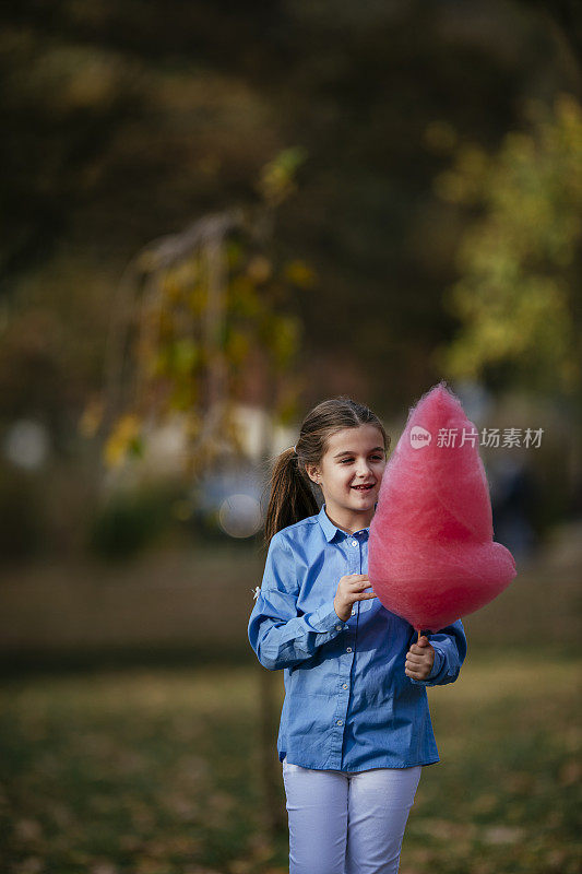 快乐的女孩在公园吃棉花糖