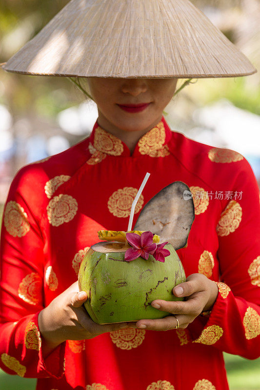 异国情调的传统越南女孩，同时提供新鲜的椰果和鲜花