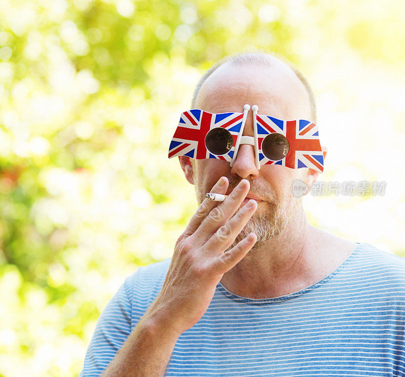 一个戴着英国国旗太阳镜的成熟英国男人抽烟，看起来很严肃