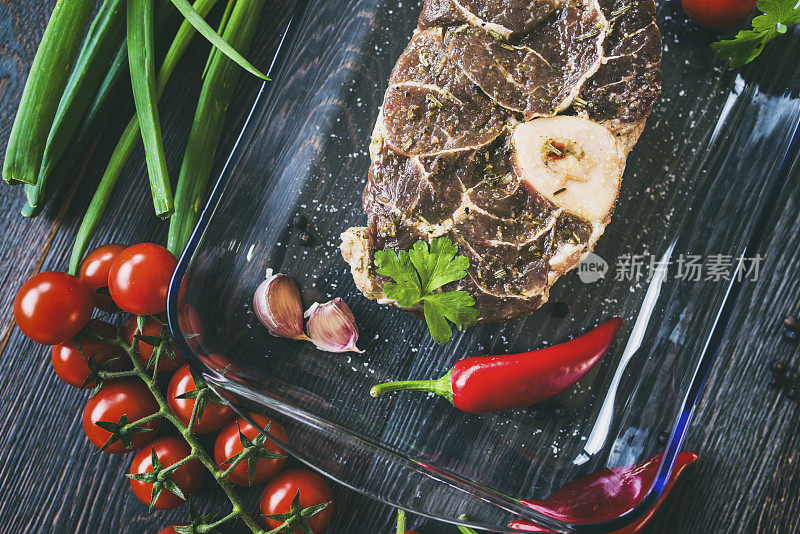 木桌上的生牛扒配香料烩牛膝和地中海新鲜蔬菜随时准备烹调