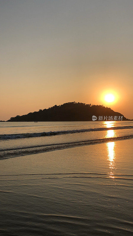 图片的海岸线帕洛伦海滩，果阿，印度在日落与橙色的日落反射在海浪拍打海滩海岸