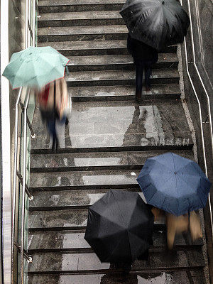 地铁楼梯上撑着雨伞的人们的鸟瞰图