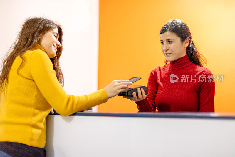 年轻女子在酒店前台用智能手机付款