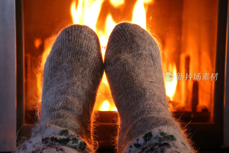 脚上穿着羊毛袜子，在壁炉旁暖着