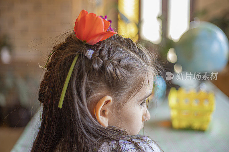 一个头发上戴着花的小女孩的后视图肖像