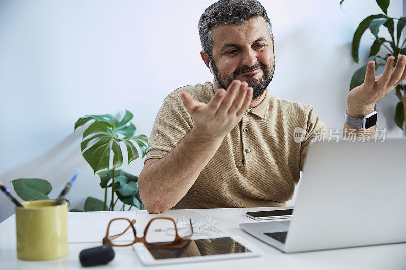 一个年轻人在他的家庭办公室里对着电脑说话