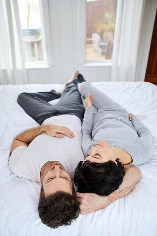 早上，一对穿着睡衣的年轻夫妇躺在床上