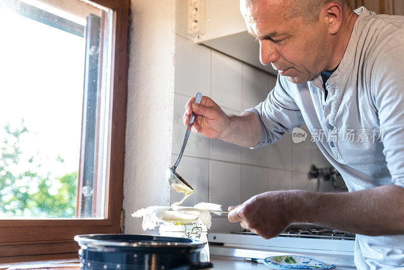 男人在家庭厨房柜台与精度过滤泡沫从融化黄油，以使一个完美的酥油