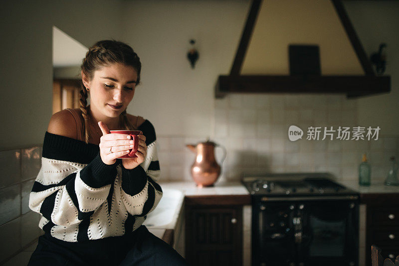 一个年轻女人在厨房里用杯子喝水