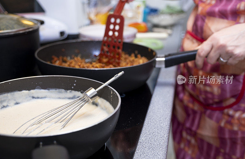 这个女人正在准备食物，意大利面卷。炸碎肉和做酱汁。