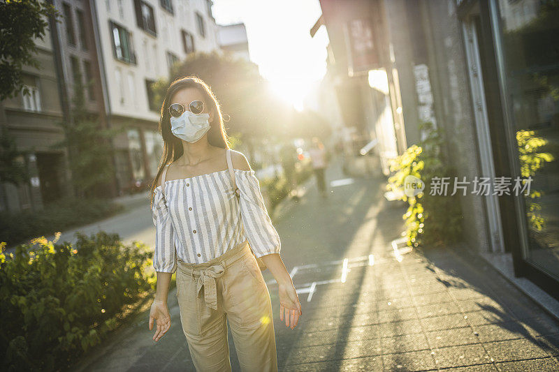 为预防冠状病毒和防雾霾，年轻妇女戴着口罩上街的肖像
