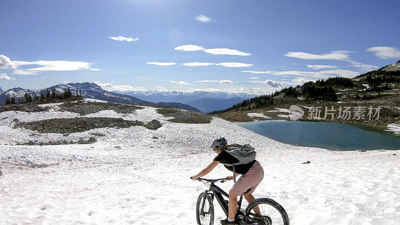 一名年轻女子骑着山地电动自行车滑下雪坡