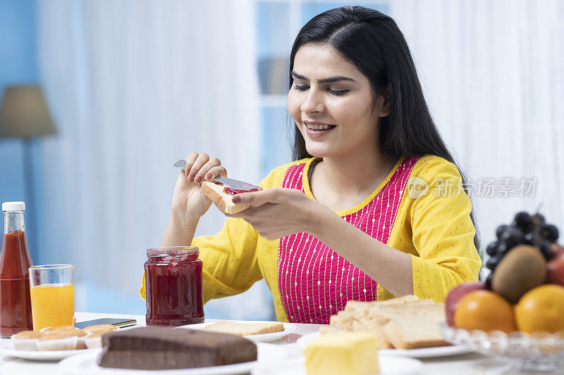 印度妇女在家里吃早餐库存照片